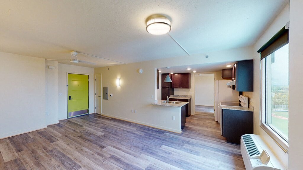 an empty living room and kitchen with a green door