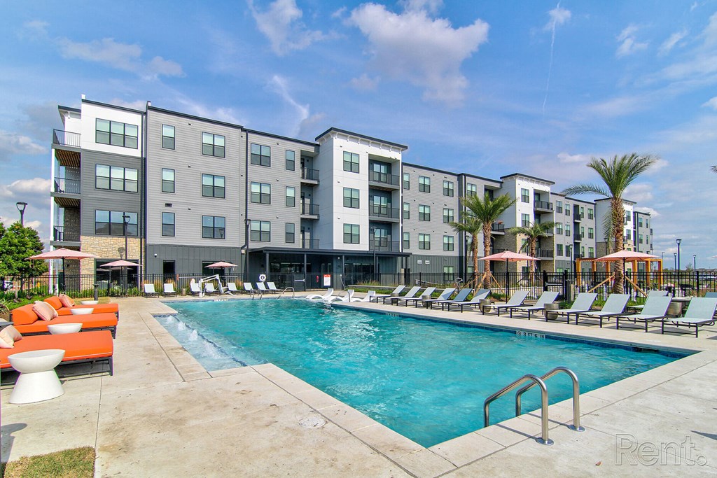 a swimming pool with orange chairs and a building in the background