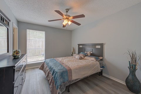 A bedroom with a bed, dresser, and a ceiling fan.