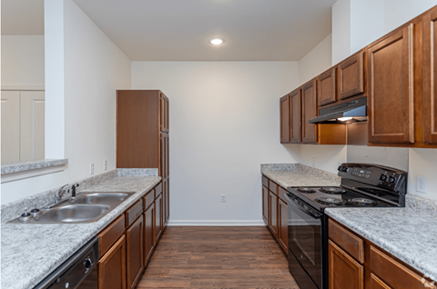 a kitchen with wood cabinets and granite counter tops and a black stove and refrigerator