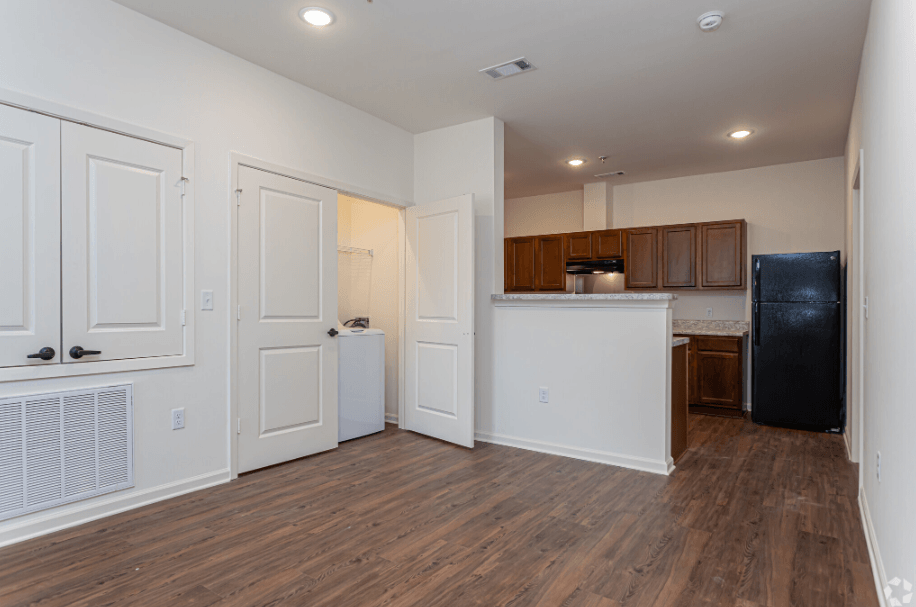 an empty living room and kitchen with white walls and wood flooring