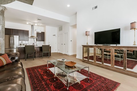 A living room with a glass coffee table and a leather couch.