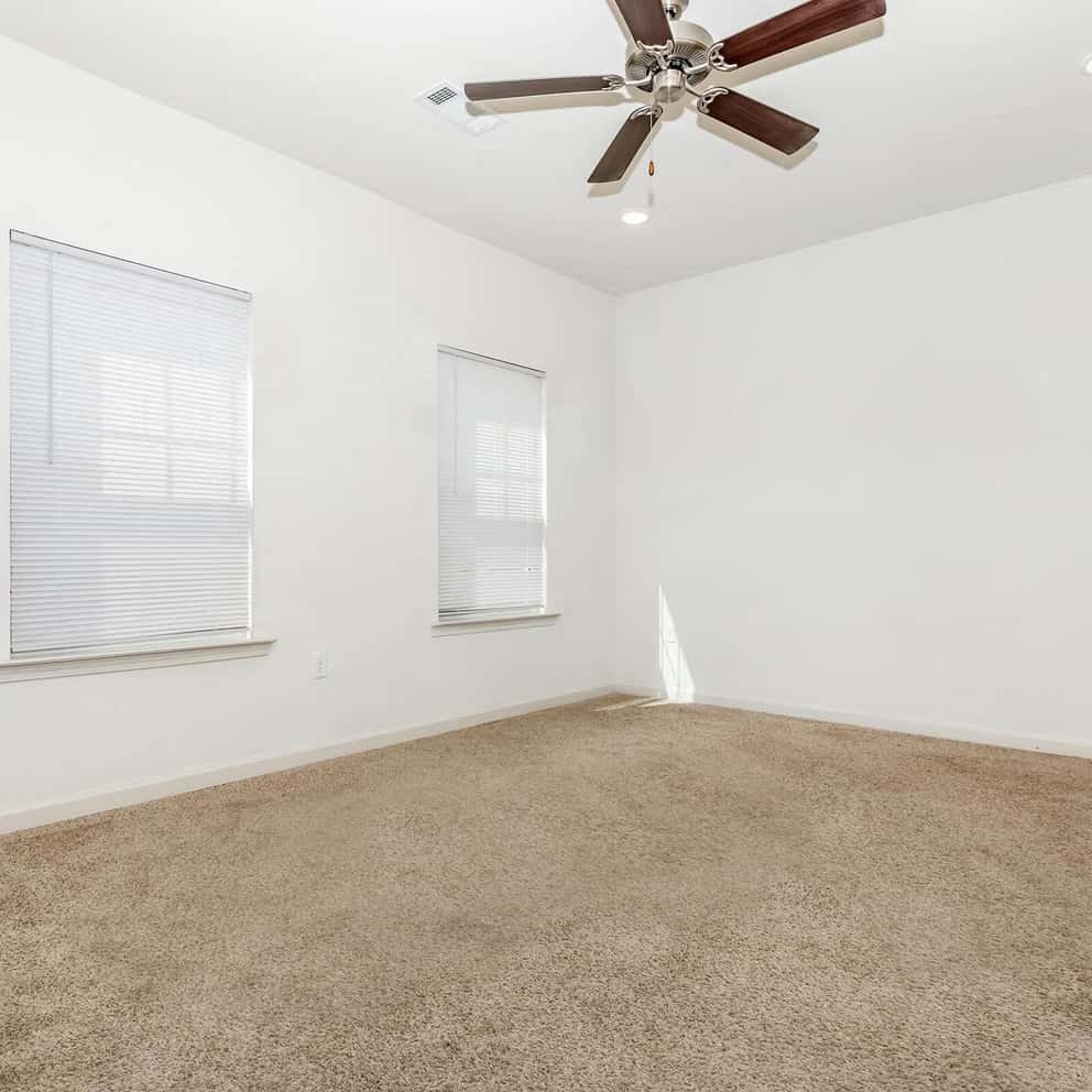 a white carpeted bedroom with a fan