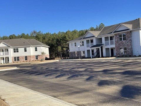 an empty parking lot in front of two apartment buildings