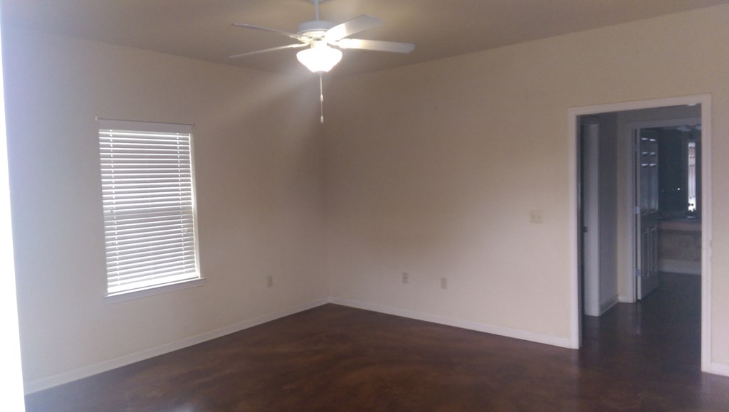 an empty living room with a ceiling fan