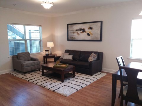 A living room with a black couch and a painting on the wall.
