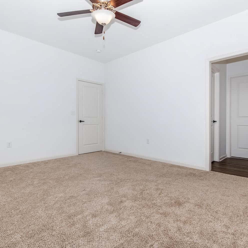 an empty room with a ceiling fan and a door