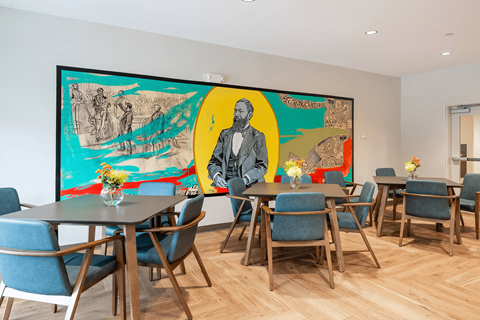 A dining room with a large painting on the wall and blue chairs.