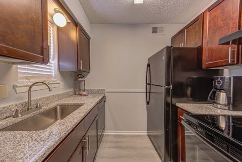A kitchen with a black refrigerator and brown cabinets.