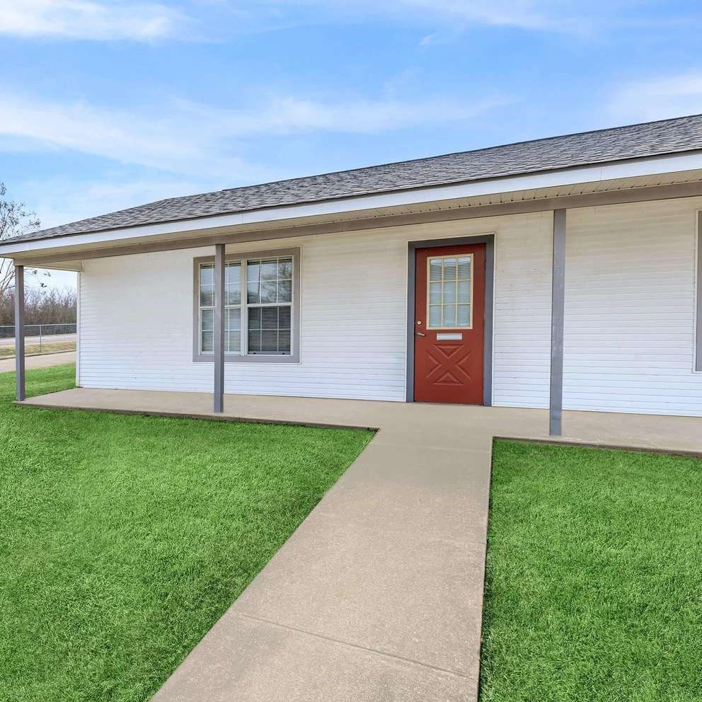 A small white building with a red door and a grey roof.