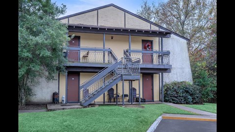 A two-story house with a red door and a balcony.