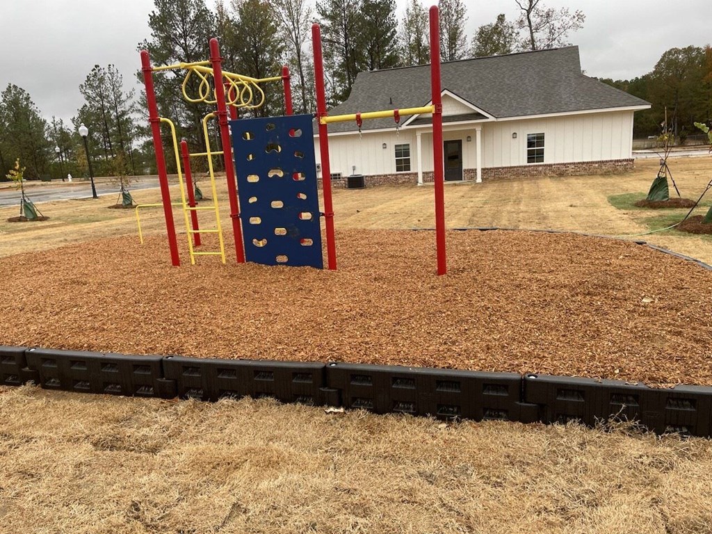 a playground with a blue rock wall in front of a house
