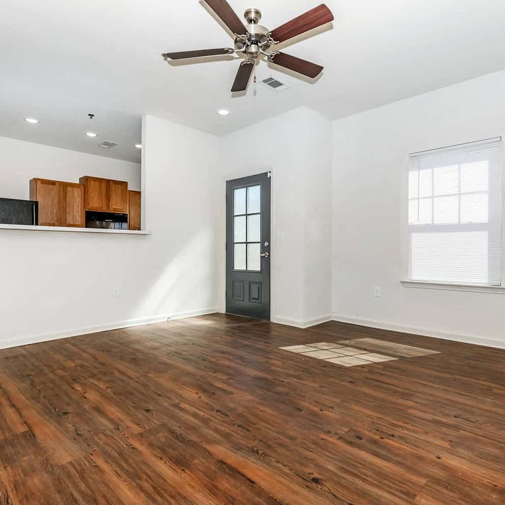 a room with hardwood floors and white walls with a ceiling fan