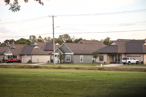 a row of houses on a street in front of a grass field