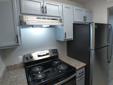 A kitchen with a black stove top oven and a black refrigerator.