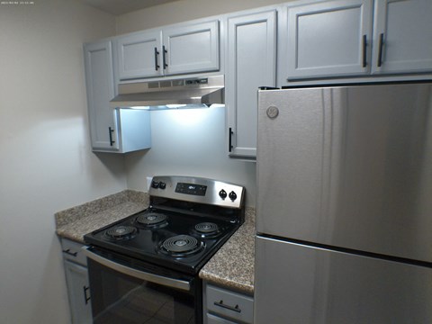 a kitchen with white cabinets and a stove and refrigerator