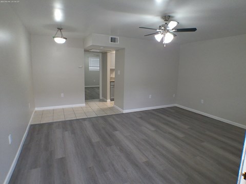 an empty living room with wooden floors and a ceiling fan
