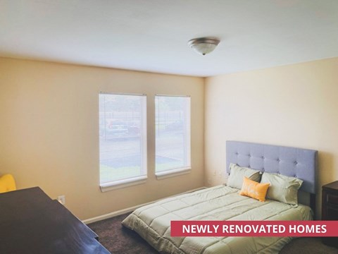 A bedroom with a bed, desk, and window.