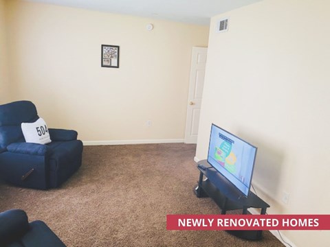 A living room with a blue chair and a flat screen TV.