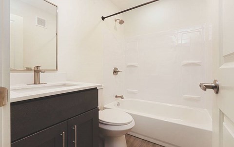 A white toilet sits next to a white bathtub in a bathroom.