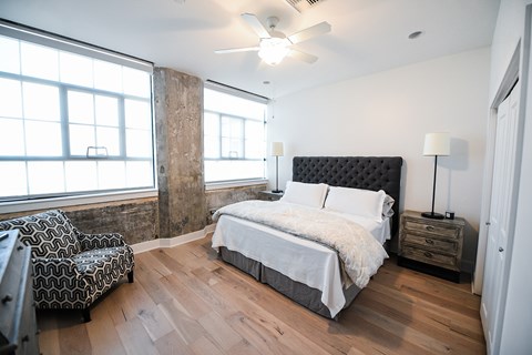 A bedroom with a large bed and a chair in front of a window.
