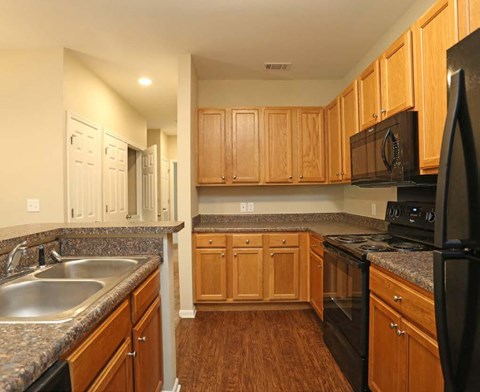 A kitchen with wooden cabinets and a black refrigerator.