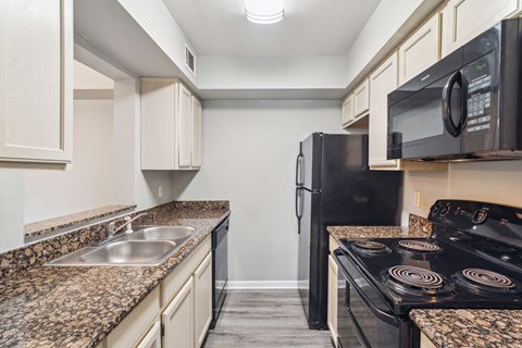 A kitchen with granite countertops and a black refrigerator.