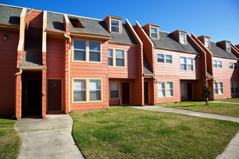 A row of red brick houses with green lawns in front.