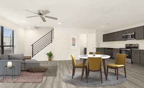 A modern living room with a grey sofa, a grey armchair, a grey side table, a grey rug, a white table, a white ceiling fan, a white door, a white wall, a black staircase, a