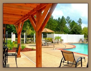 A pool area with a wooden pergola and chairs.