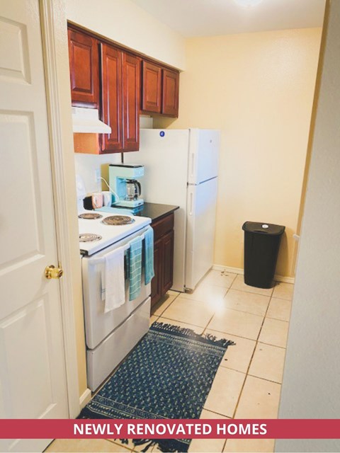A kitchen with a white fridge, white oven, and a black trash can.