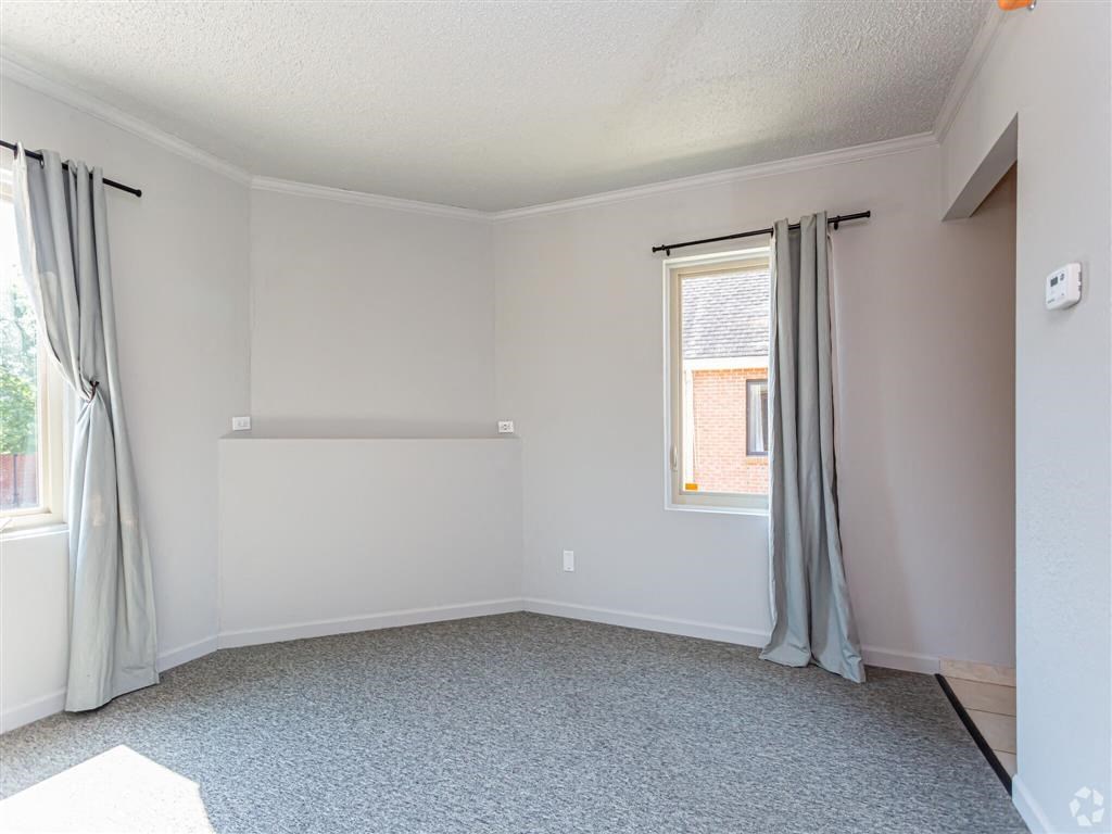 an empty living room with a window and curtains