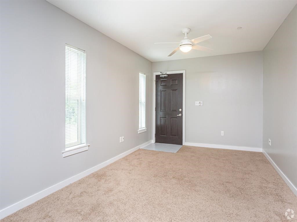 an empty living room with a ceiling fan and a door