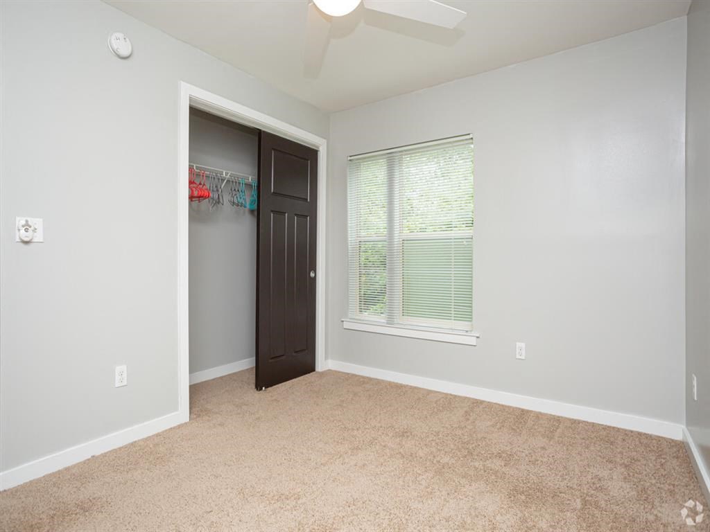 a bedroom with a closet and a window and a ceiling fan