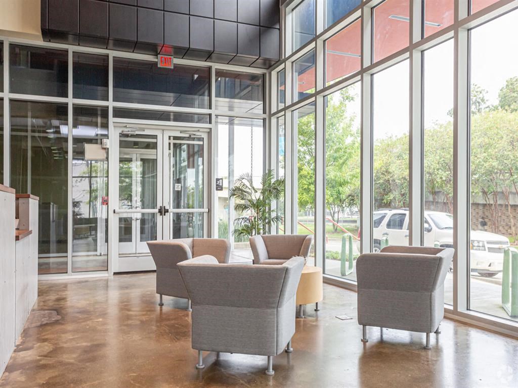a lobby with couches and chairs in a building with glass doors