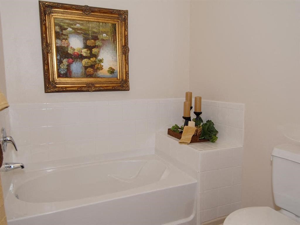 a bathroom with a white tub and a picture on the wall