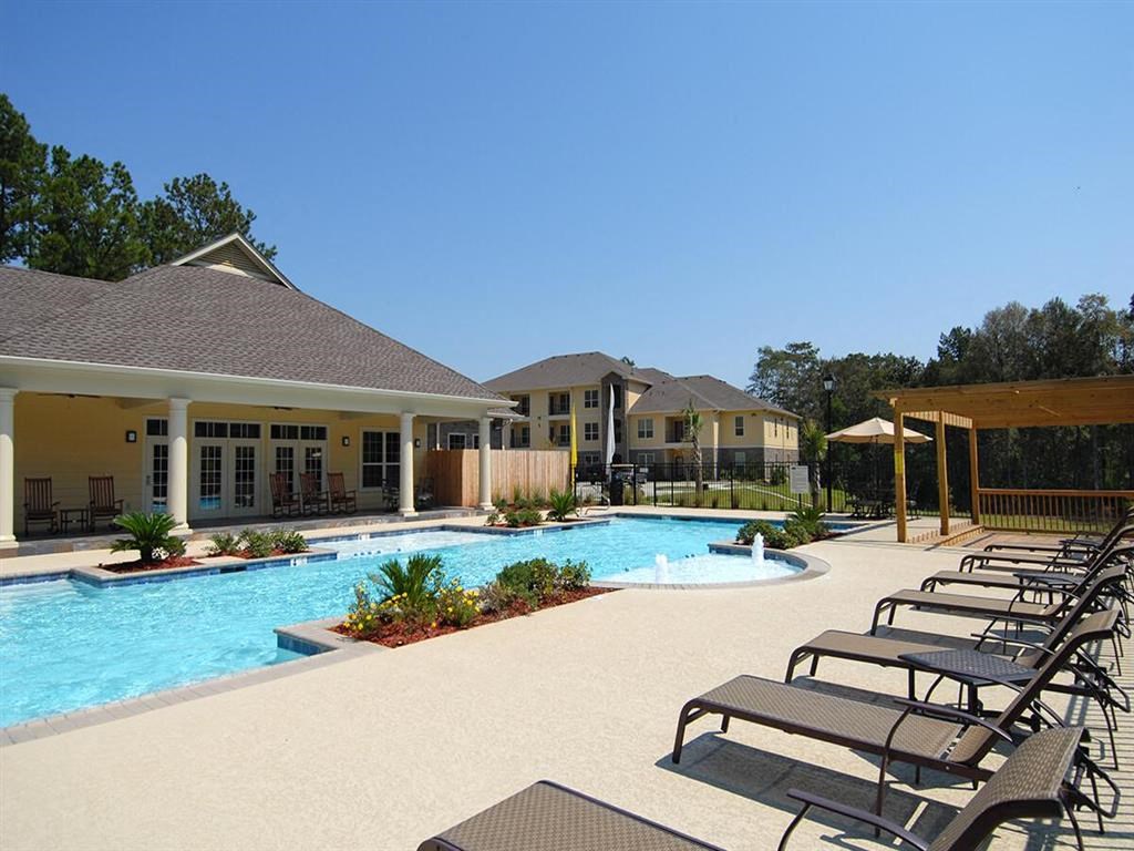 a large swimming pool with chairs in front of a building