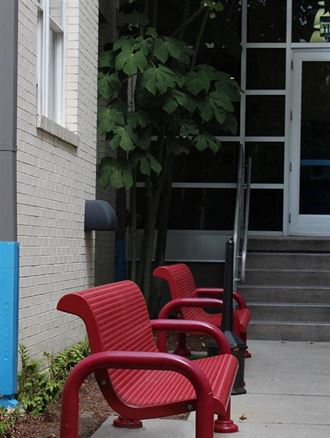 three red chairs sitting outside of a building