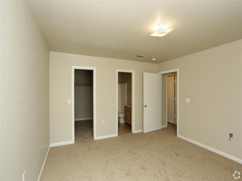 an empty living room with doors to the bathroom and a closet