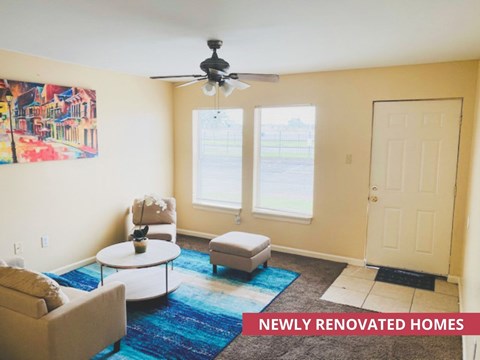 A living room with a ceiling fan and a painting on the wall.
