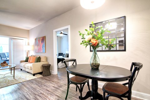 A dining room with a table set for two and a couch with pillows at Silver Oaks Apartments, Gonzales, LA 70737