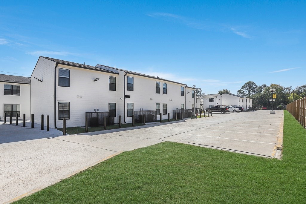 A row of white houses with a green lawn in front.