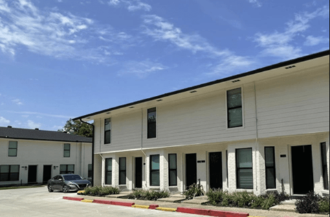 A white building with a black car parked in front.