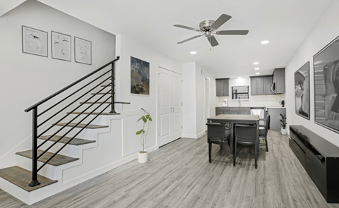 A modern interior with a staircase, a dining table, and a ceiling fan.
