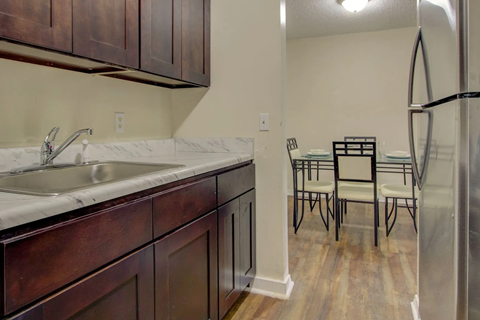 A kitchen with a white sink and brown cabinets.