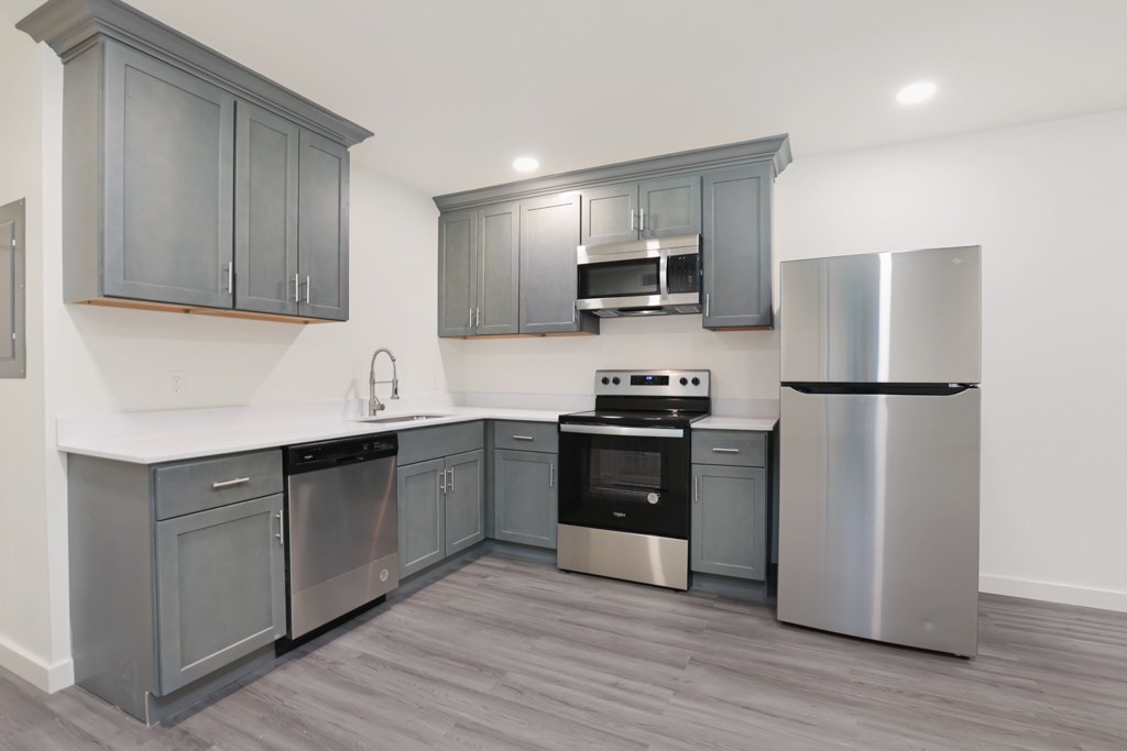 A modern kitchen with stainless steel appliances and grey cabinets.