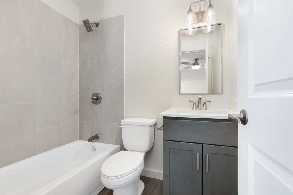 A white toilet sits next to a white bathtub in a bathroom.