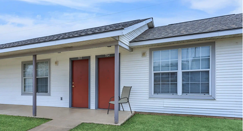 A house with a red door and a grey chair.