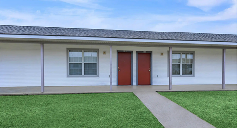 A white building with a red door and windows.