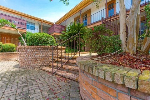 A brick wall with a metal railing and a tree in front of a building.